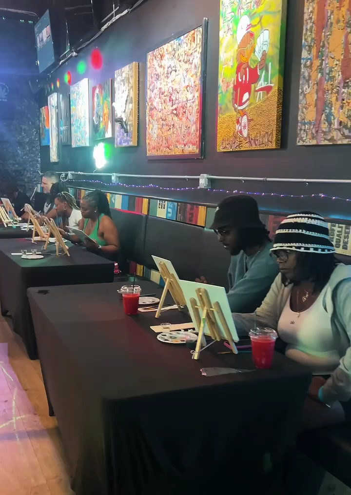 People sitting at tables in Prohibition THCafe with colorful wall art in the background